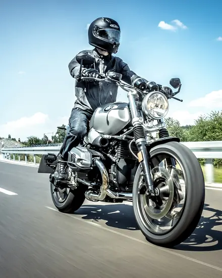 Motociclista de capacete numa estrada, num dia de sol